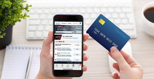 Eine Sportwetten App auf dem Smartphone und eine Kreditkarte.