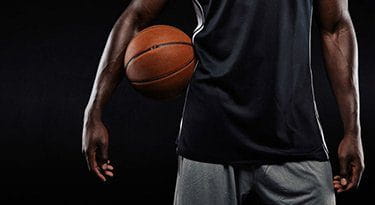 Ein Basketballspieler mit eingeklemmten Ball zwischen Arm und Oberkörper.