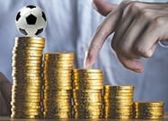 Fünf aufsteigende Stapel von Geldmünzen und auf dem höchsten befindet sich ein Ball.